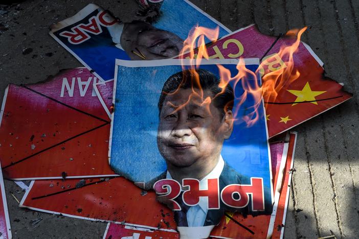 Members of the National Students' Union of India burn a poster showing Chinese President Xi Jinping during an anti-China demonstration in Ahmedabad on June 18, 2020.