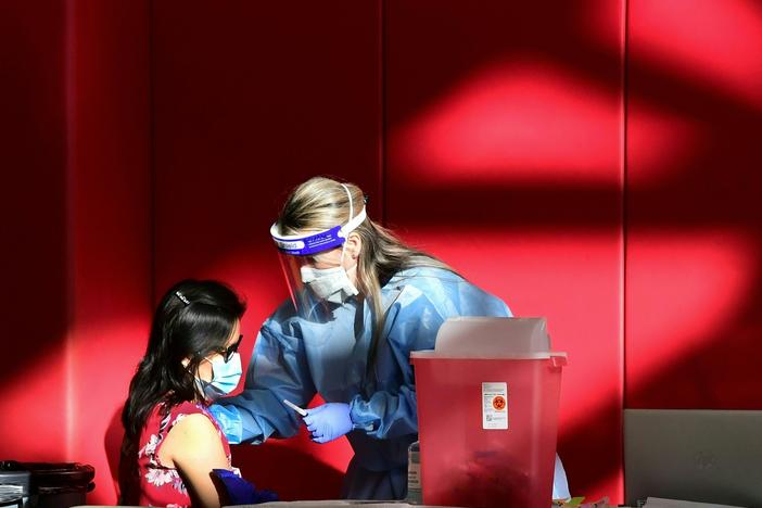 A registered nurse administers the COVID-19 vaccine at a high school gym in Corona, California. Scientists are trying to determine if vaccines (and boosters) will offer protection against the newly identified omicron variant.