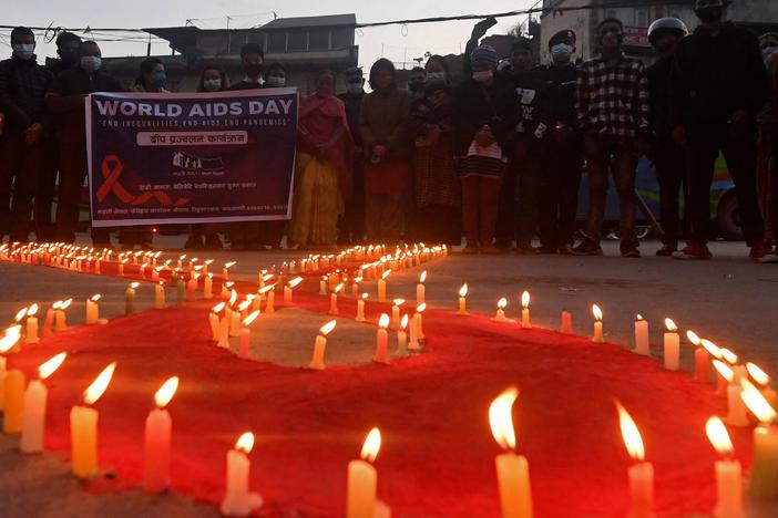 Volunteers stand after lighting candles in the shape of a red ribbon during an awareness event ahead of World AIDS Day in Kathmandu on Tuesday.
