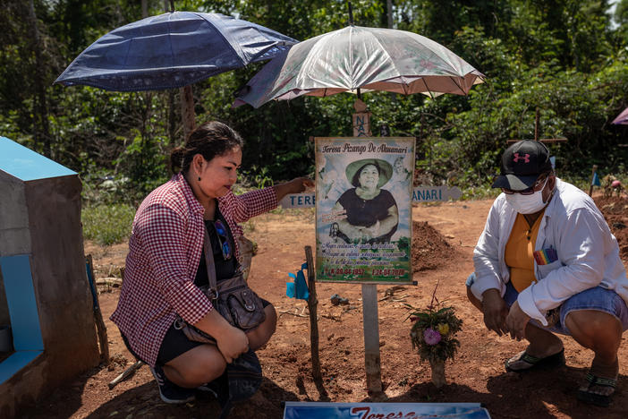 Margarita Ahuanari, left, and Karina Ahuanari look at posters of their mother. The images were placed where they think she was buried at the mass grave that was later renamed the COVID-19 Cemetery in Iquitos.