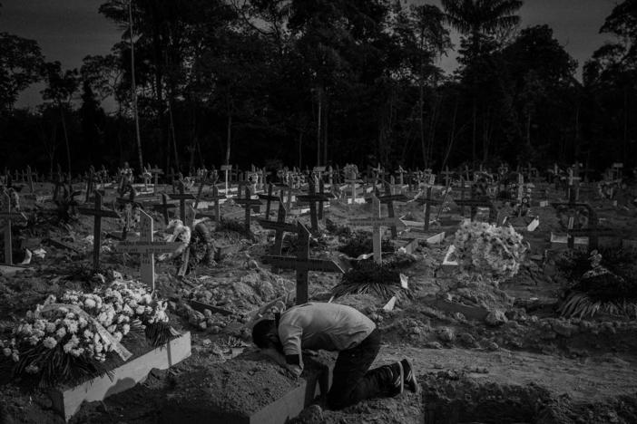 A man cries over his mother's grave in the Nossa Senhora Aparecida cemetery, in Manaus, Amazonas, Brazil, on Sept. 29, 2020. Iris Gonçalves Alves died at age 54 the previous day from COVID-19, according to the information on her burial record. During the worst times of the pandemic in Manaus, only three relatives could attend a burial in its cemeteries.