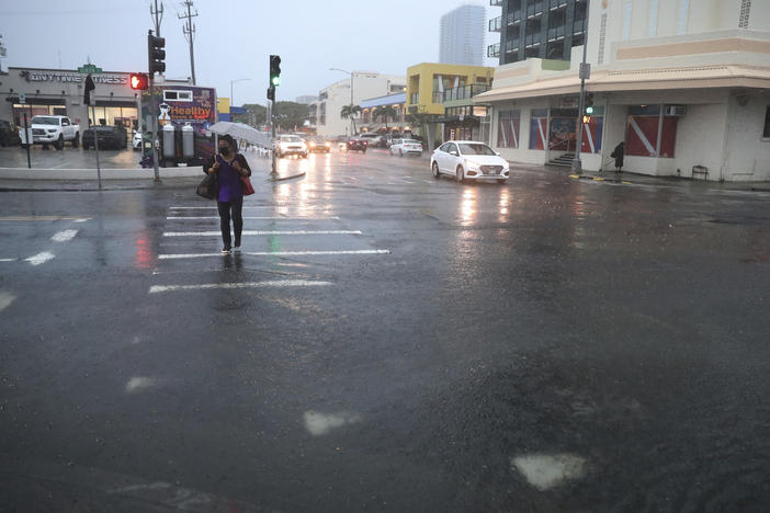 A pedestrian tries to cross a flooded Queen Street, Monday, Dec. 6, 2021, in Honolulu.