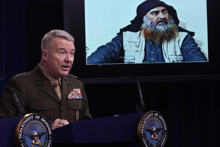 Marine Corps Gen. Kenneth McKenzie, commander of U.S. Central Command, speaks as a picture of Abu Bakr al-Baghdadi is displayed during a news briefing on Oct. 30, 2019, at the Pentagon in Arlington, Virginia. McKenzie spoke to reporters to provide an update on the special operations raid that targeted the Islamic State leader in Idlib province, Syria.