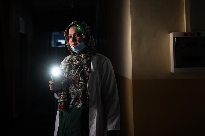 Dr. Elaha Ibrahimi uses her phone as a flashlight during a power cut inside the hospital in Mirbacha Kot, Afghanistan, in October. Health care workers have continued to work without salaries, without medicine for patients and with frequent power cuts.