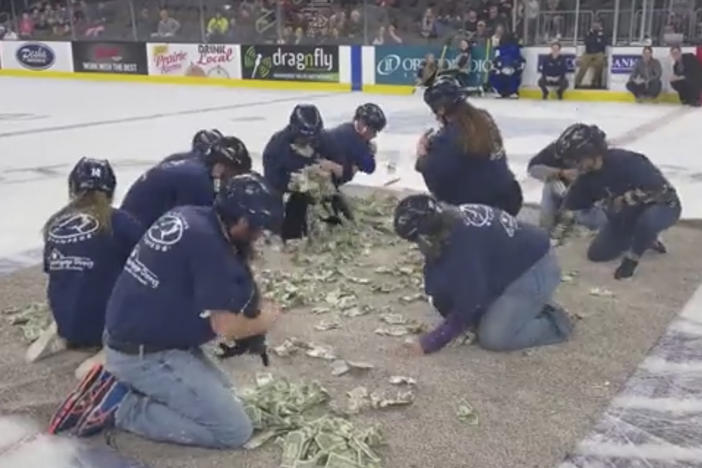 Area teachers in Sioux Falls, S.D., scramble to grab $1 bills on the ice rink at a Sioux Falls Stampede hockey game on Saturday, in this screenshot from a video posted by <em>Argus Leader</em> reporter Annie Todd that went viral this weekend.