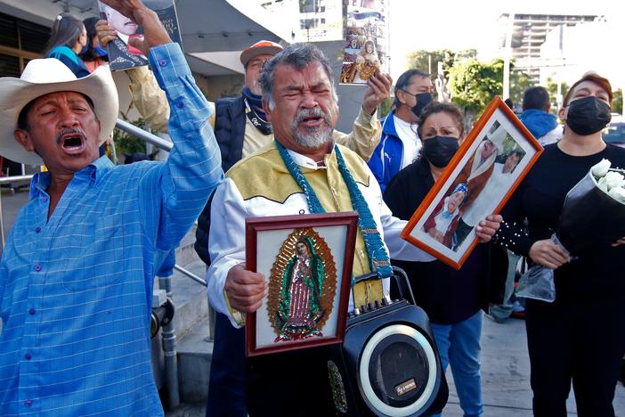 Fans of Mexican singer Vicente Fernández sing his songs as they hold his picture and the image of the Virgin of Guadalupe, outside the Country 2000 hospital where he died, in Guadalajara, Mexico, on Dec. 12.