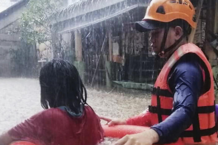 In this handout photo provided by the Philippine Coast Guard, a rescuer assists a girl as they wade through flooding caused by Typhoon Rai in Cagayan de Oro City, southern Philippines.