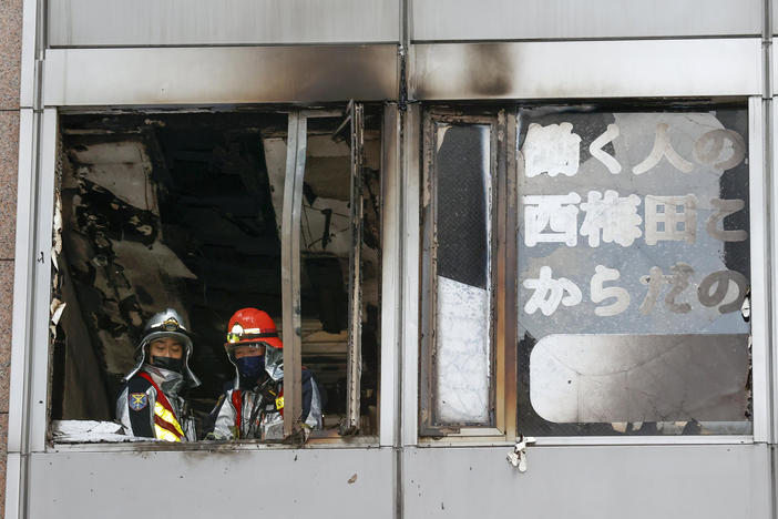Firefighters stand on a floor at a building where a fire broke out Friday in Osaka, Japan, killing 24 people.