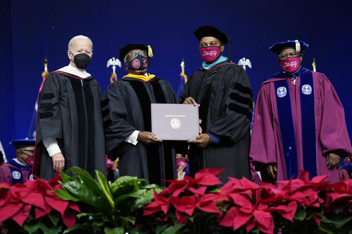 Rep. Jim Clyburn, D-S.C., second from left, holds his history degree with South Carolina State University Interim President Alexander Conyers, second from right, on stage with President Biden and Rodney Jenkins, chair of the Board of Trustees, right, during the South Carolina State University's 2021 Fall Commencement Ceremony in Orangeburg, S.C., on Friday.