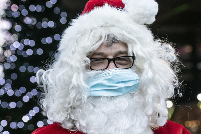 A Santa Claus in Germany wears a surgical mask in December 2020. If you're planning to take the kids to see Santa this year, experts say it's safest to keep everyone's masks on.