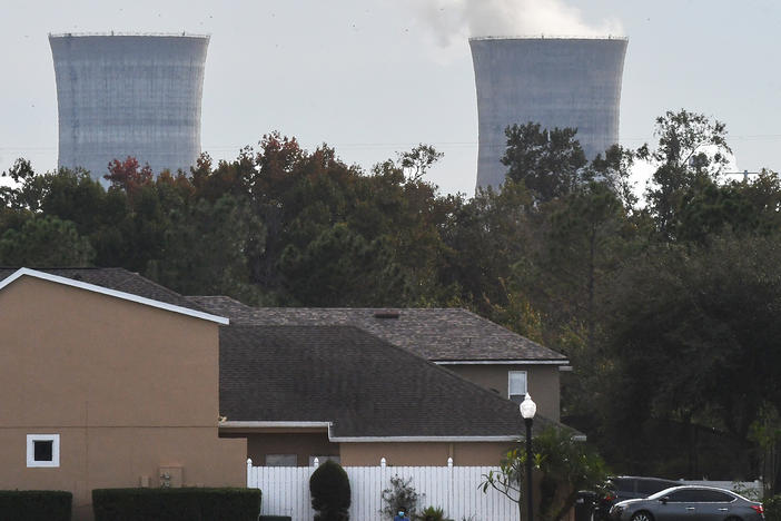 The cooling towers at the Stanton Energy Center, a coal-fired power plant, are seen behind a home in Orlando.
