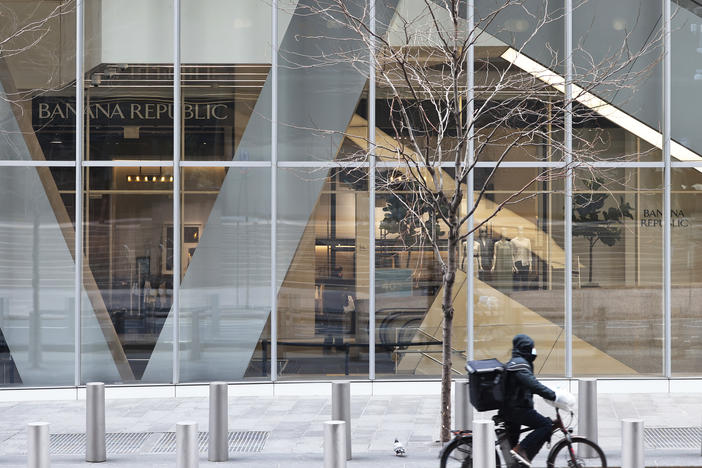 A delivery person rides a bicycle past a storefront in New York City.