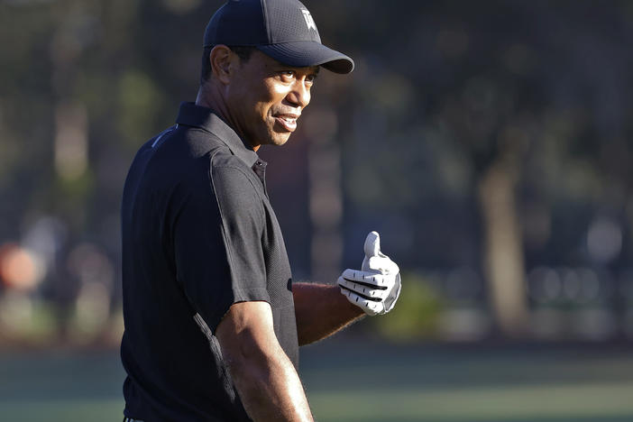 Tiger Woods smiles and gestures as he prepares to tee off during the first round of the PNC Championship golf tournament Friday in Orlando, Fla. Woods is back playing after getting injured in a car accident. He is paired with his son Charlie during the tournament.