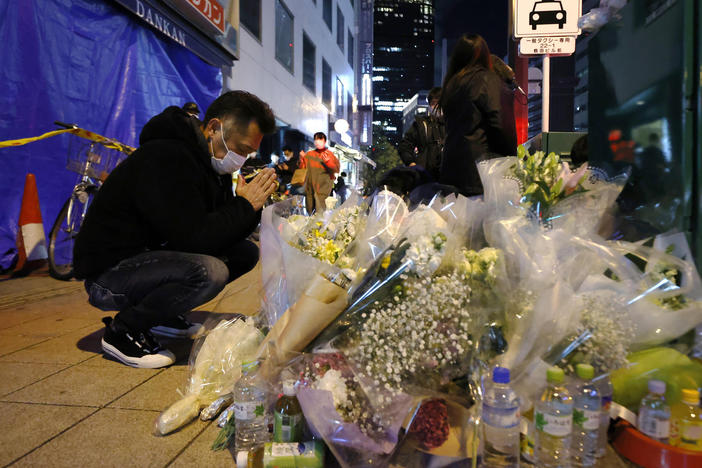 A mourner prays in front of offerings near a building where a fire broke out, in Osaka, western Japan on Saturday. Japanese police on Sunday identified a 61-year-old man as a prime arson suspect.
