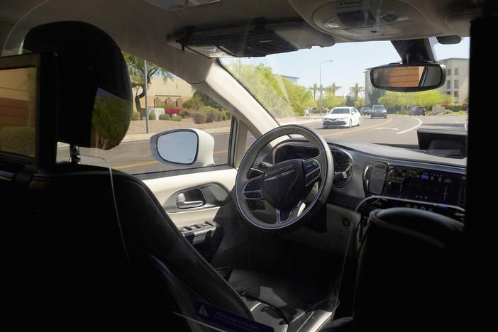 A Waymo minivan moves along a city street during an autonomous vehicle ride on April 7 in Chandler, Ariz. Waymo, a unit of Google parent Alphabet Inc., is one of several companies testing driverless vehicles in the U.S. Auto makers are also developing self-driving technology but it still requires human drivers to take over when required.