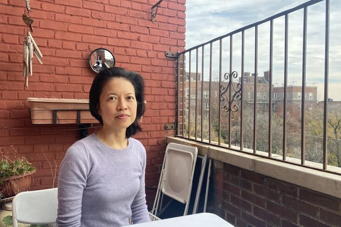 Beata Moon sits on the balcony of her Queens, New York, apartment on Dec. 9. Because she is not fully vaccinated, much of New York City is off-limits to her.