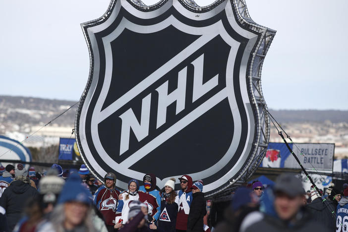 Fans pose below the NHL logo outside Falcon Stadium at the Air Force Academy in Colorado Springs, Colo., in February 2020.