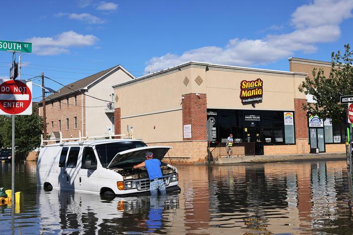 Abilio Viegas attempts to fix his flooded van on South Street in Newark, New Jersey after flooding cause by the remnants of Hurricane Ida.