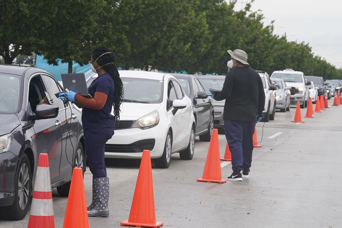 Employees of Nomi Health check in a long line of people seeking COVID-19 tests Tuesday in North Miami, Fla. The omicron variant has unleashed a fresh round of fear and uncertainty for travelers, shoppers and partygoers across the U.S.