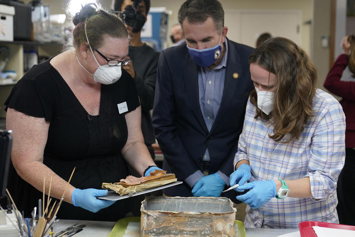 Virignia Gov. Ralph Northam ( center) watches as lead conservator for the Virginia Department of Historic Resources, Kate Ridgway (left) and Sue Donovon, conservator for Special Collections for the University of Virginia, remove the contents of a time capsule  from the pedestal that once held the statue of Confederate General Robert E. Lee.