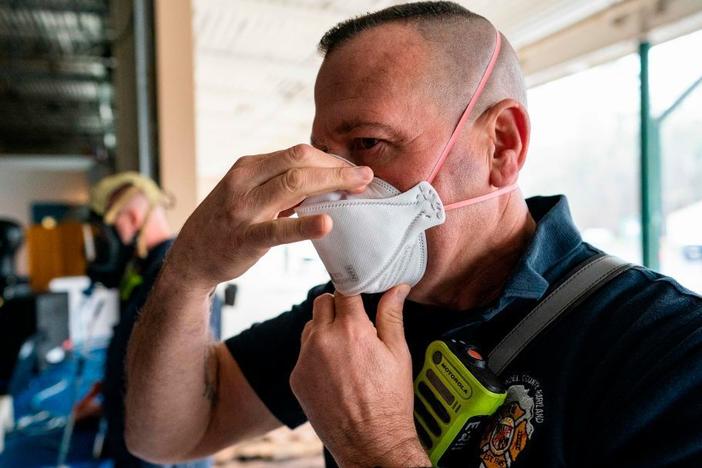 A firefighter tests the seal on his N95 mask at the start of his shift in Glen Burnie, Md. With the spread of omicron, experts say to wear high-filtration respirators in public indoor spaces for the best protection.