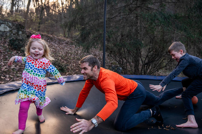 Blake Farmer plays with his kids, Louisa, 2, and Turner, 8, on the trampoline in their backyard in Nashville, Tennessee. After Thanksgiving, the family all had breakthrough COVID cases, resulting in a couple weeks spent at home. The trampoline served as a distraction for the kids, says Blake Farmer, their father.