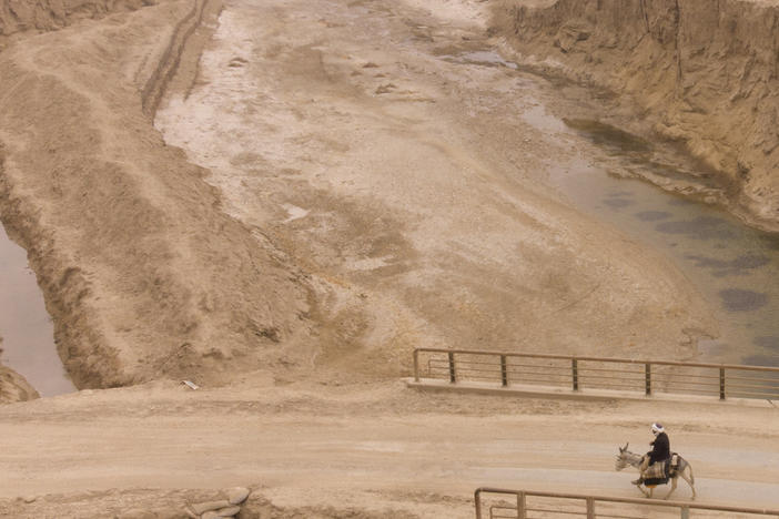 An Afghan farmer uses a donkey to carry water canisters across the dried-out river near Sang-e-Atash, Afghanistan. A severe drought has dramatically worsened the already desperate situation in the country.