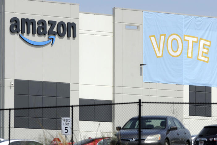 A banner encouraging workers to vote in labor balloting is shown at an Amazon warehouse in Bessemer, Ala., on March 30. The company has reached a settlement with the National Labor Relations Board to allow its workers to organize freely and without retaliation.