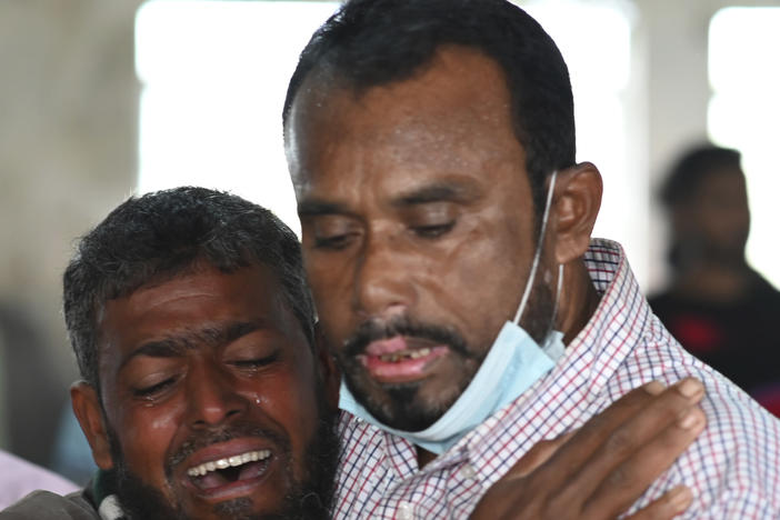 A person consoles his relative who is unable to find his five year old son travelling on a ferry which caught fire on the Sugandha River. Bangladesh fire services say at least 37 passengers have been killed.