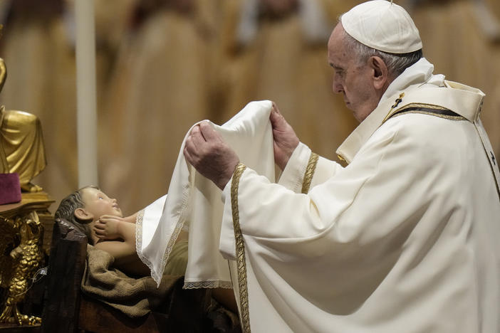 Pope Francis unveils a statue of Baby Jesus as he celebrates Christmas Eve Mass at St. Peter's Basilica, at the Vatican, on Friday.