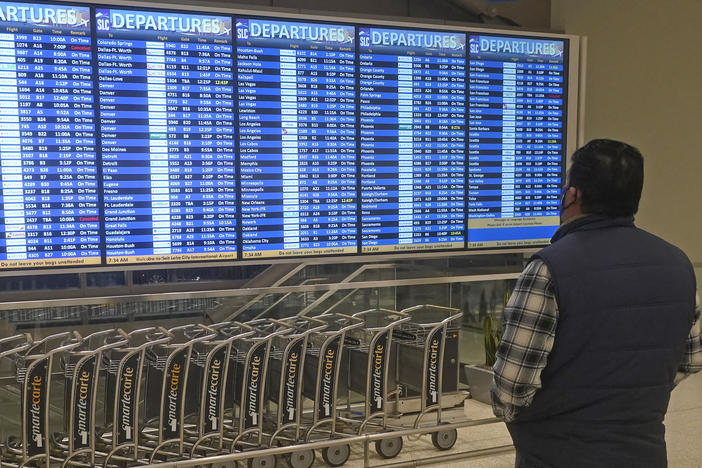 A man looks at the departures board at Salt Lake City International Airport on Friday. Hundreds more flights in the U.S. were canceled on Christmas Day — most involving Chinese airlines, as well as Delta and United in the U.S.
