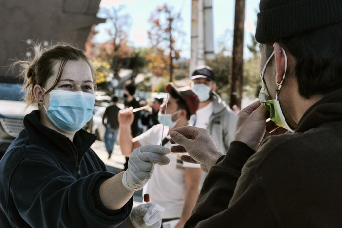 A man is handed a swab for a rapid test as people line up for coronavirus testing at a gas station in the Reseda section of Los Angeles on Sunday.