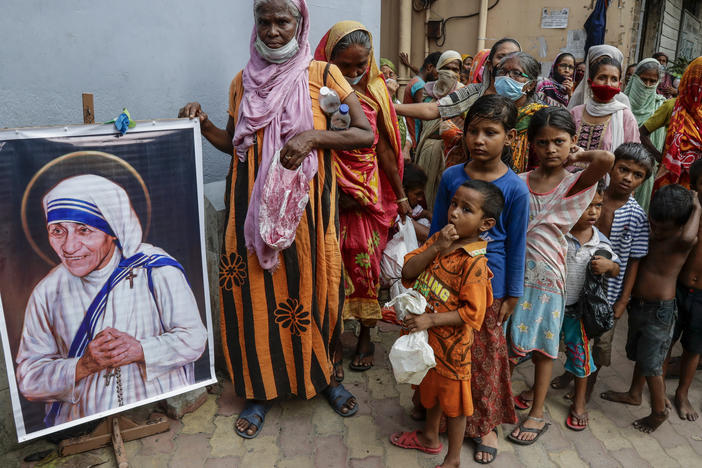Homeless people gather beside a portrait of Saint Teresa, the founder of the Missionaries of Charity, to collect free food outside the order's headquarters in Kolkata, India, in August.