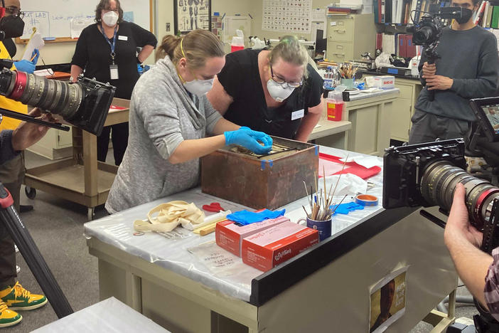 Virginia conservators unpack a box left in the pedestal at the former site of a statue of Confederate Gen. Robert E. Lee, in Richmond, Va., on Tuesday.