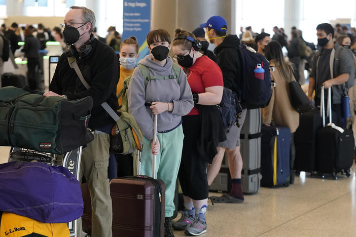 Travelers wait in the ticketing line at Salt Lake City International Airport on Monday. There have been thousands of flight delays and cancellations as the omicron variant spreads across the country. Unionized flight attendants are wary of new CDC guidelines that shorten the isolation period.