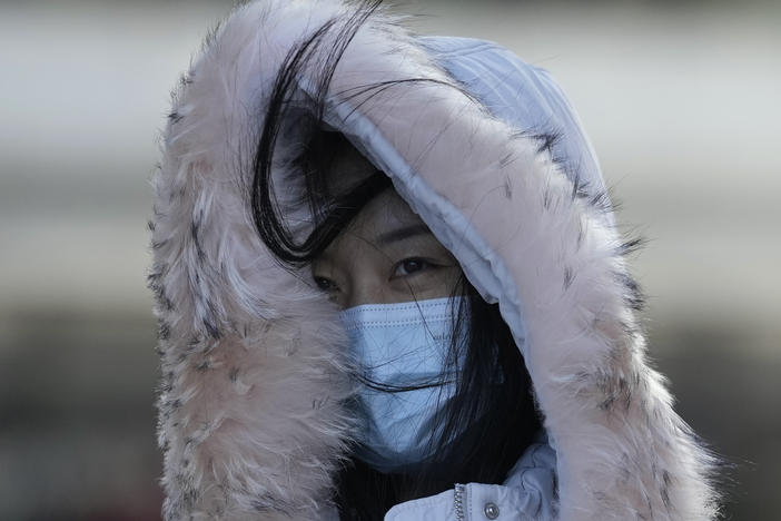 Women wearing masks to help curb the spread of the coronavirus walk against cold strong winds in Beijing, China, Thursday, Dec. 30, 2021.