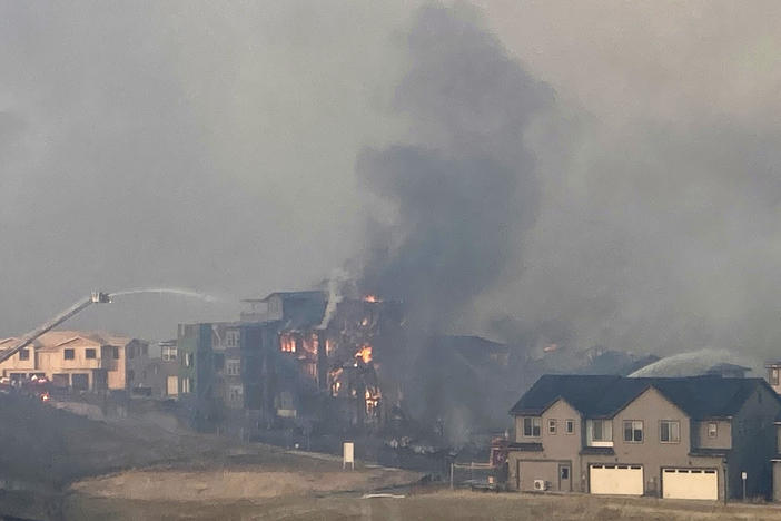Firefighters spray water on a structure fire as a wildfire burns on Thursday in Superior, Colo.