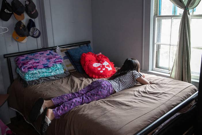 A 8-year-old looks out her bedroom window during self-quarantine with her family due to COVID-19.