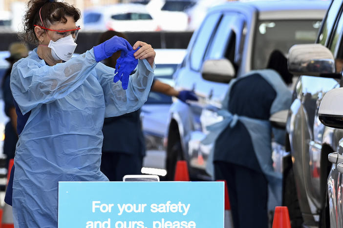 Health care workers administer COVID-19 tests at a drive-through clinic in Sydney, Friday, Dec. 31. Australian health authorities have reported a record 32,000 new virus cases, many of them in Sydney.