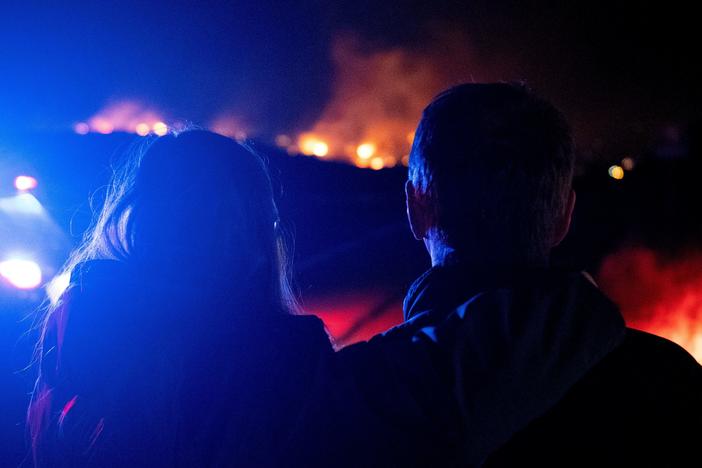 Dr. Bonnie Abbott (left) embraces her husband George as they watch flames engulf homes as the Marshall Fire spreads through a neighborhood in the town of Superior in Boulder County, Colorado on Thursday.