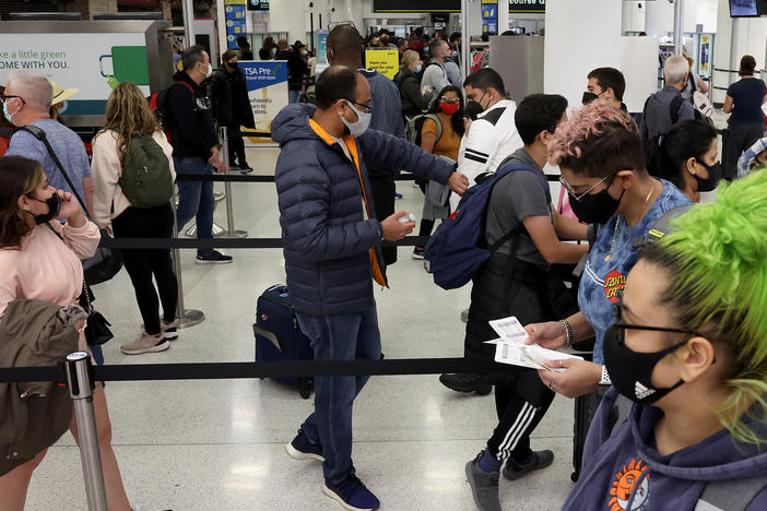 Travelers make their way through Miami International Airport on Tuesday. Airlines canceled more than 2,400 U.S. flights by midday on Saturday, according to the flight tracking website FlightAware.