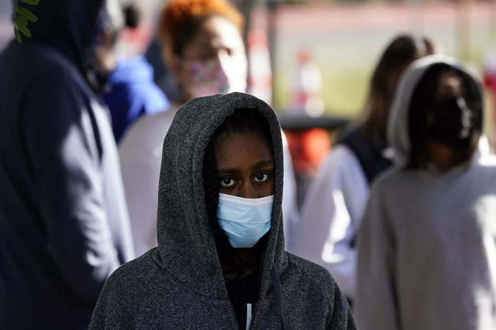 A young person wears a mask while waiting in line at a COVID-19 testing site on the Martin Luther King Jr. medical campus on Monday in Los Angeles.