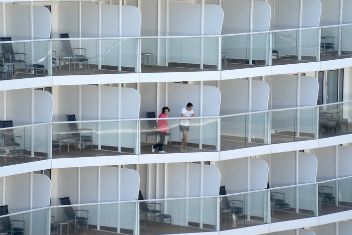 Passengers look out from the Spectrum of the Seas cruise ship docked in Hong Kong on Wednesday. Thousands of passengers were being held on the ship for coronavirus testing after health authorities said nine passengers were linked to a recent omicron cluster and ordered the ship to turn back.