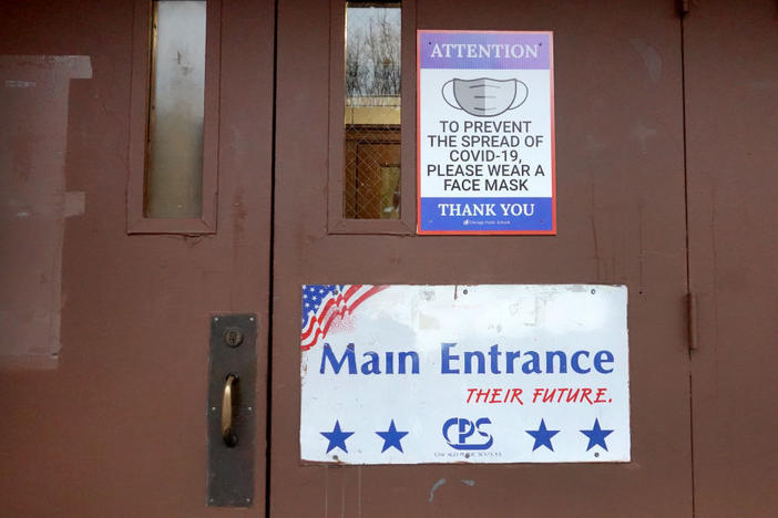 A sign on the door of Lowell Elementary School asks students, staff and visitors to wear a mask to prevent the spread of COVID-19 on Wednesday in Chicago. Classes at all of Chicago public schools have been canceled Wednesday by the school district after the teachers union voted to return to virtual learning.
