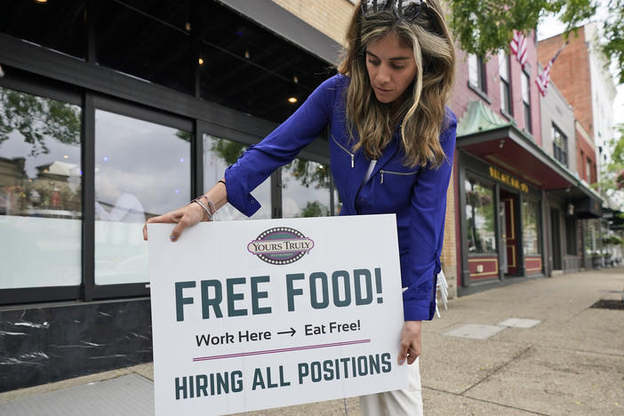 An employee at a restaurant in Chagrin Falls, Ohio, puts up a sign on June 3, 2021, looking for workers with the promise of free food for new hires.