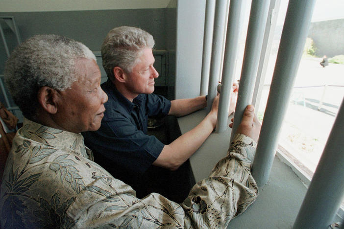 Nelson Mandela and former U.S. President Bill Clinton look to the outside from Mandela's Robben Island prison cell in Cape Town, South Africa, in this photo from March 27, 1998.