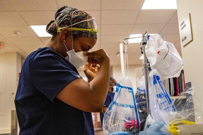 A medical worker puts on a mask before entering a negative pressure room with a COVID-19 patient in the ICU ward at UMass Memorial Medical Center in Worcester, Mass., last week.