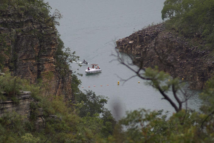 A boat navigates on the Furnas reservoir on Sunday after a massive slab of rock broke away from a cliff and toppled onto pleasure boaters on Saturday, killing at least 10 people near Capitolio city, Brazil.