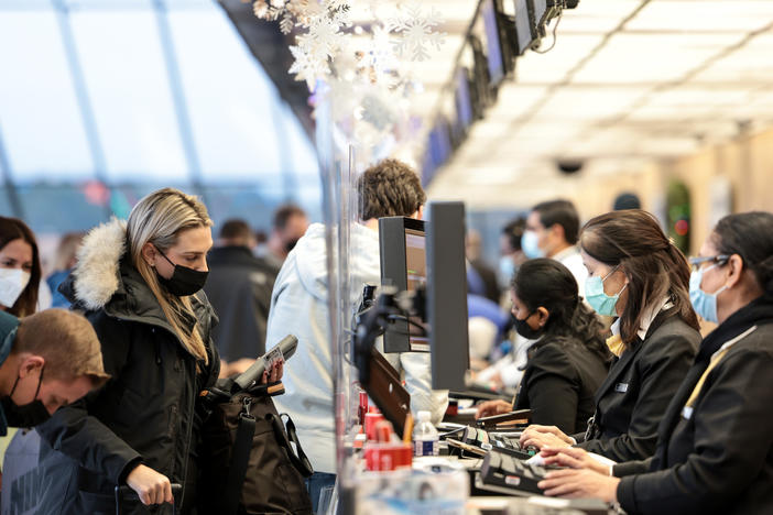 A woman checks in for her flight at a United Airlines counter at Dulles International Airport on December 27, 2021.