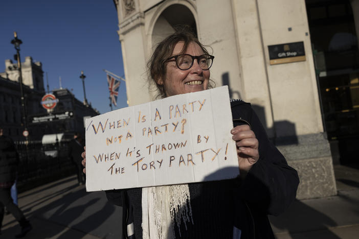 A protester holds a sign outside of Parliament in London after the weekly Prime Minister's Questions session, in which Boris Johnson said he joined staff for an outdoor party at 10 Downing Street in May 2020.